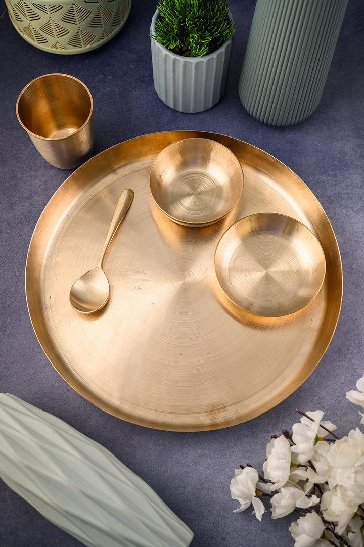 Kansa Dinner set displayed on a table with bowls and a spoon, showcasing its handmade bronze craftsmanship.