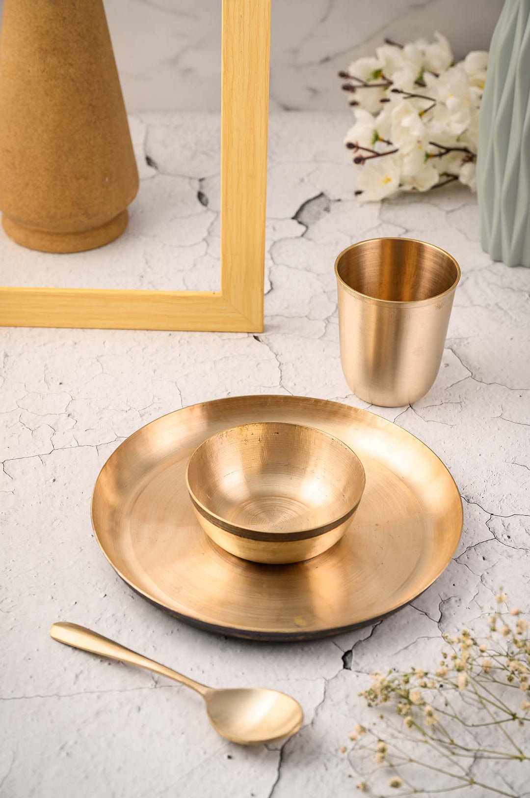 Kansa Baby Dinner Set / Baby Gift Set featuring a bronze plate, bowl, spoon, and glass on a decorative table.